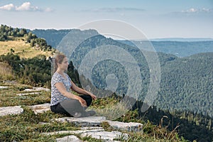 Young woman relax and meditate alone at top of mountain in warm summer day, healthy lifestyle