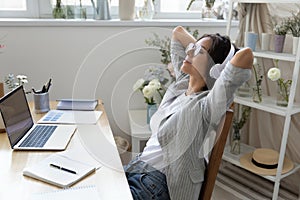 Young woman relax at workplace listen to music in headphones