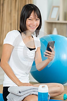 young woman relaxes with phone after yoga photo