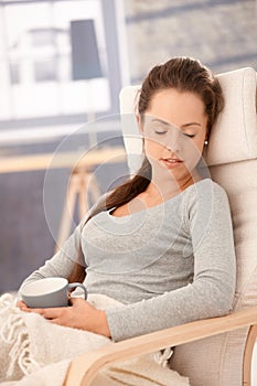 Young woman relaxing in armchair eyes closed