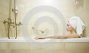 Young woman relaxing in bathtub. Beautiful girl in towel