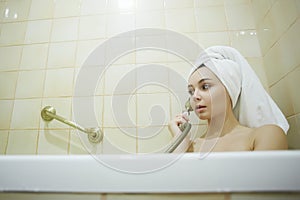 Young woman relaxing in bathtub. Funny girl in towel