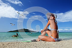 Young woman relaxing on the beach enjoying the flying birds against the green islands