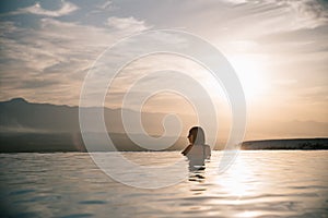 young woman relaxing in beautiful pool at sunset