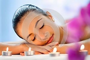 Young woman relaxing in dimmed candle light after massage.