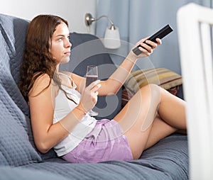 Woman relaxing at evening with glass of red wine on sofa