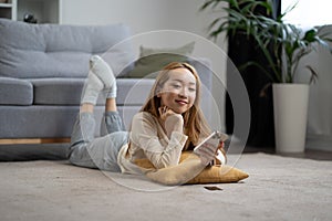 Young Woman Relaxing on Floor With Smartphone in Modern Home