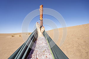 Young woman relaxing in green hammock with view on sand dunes of Sahara Desert, Morocco