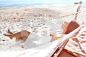 Young woman relaxing in hammock on beach