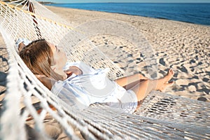 Young woman relaxing in hammock on beach