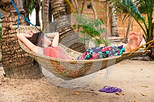 Young woman relaxing in a hammock on the beach during summer holiday photo