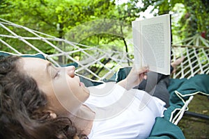 Young woman relaxing in hammock with book