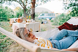 Young woman relaxing in hammock outdoors, in the backyard garden. Enjoying summer