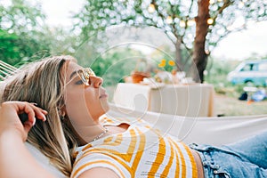 Young woman relaxing in hammock outdoors, in the backyard garden. Enjoying summer