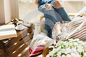 Young woman is relaxing at home, drinking tea, reading book