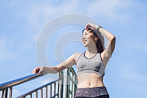 Young woman relaxing after jogging exercise on fence at park to freshen her body and enjoy warm light in morning. photo