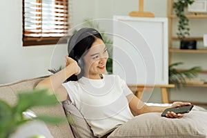 young woman relaxing and listening to the music on the phone on the couch