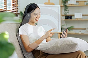 young woman relaxing and listening to the music on the phone on the couch