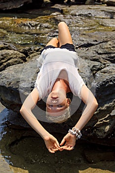 Young woman relaxing and meditating on picturesque rocky seashore