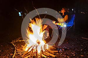 Young woman relaxing near the campfire at night