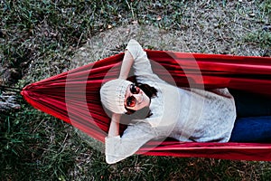 Young woman relaxing in orange hammock. Camping outdoors. autumn season at sunset