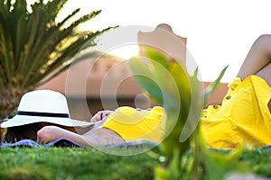 Young woman relaxing outdoors on sunny summer day. Happy lady lying down on green grass daydreaming thinking. Calm beautiful girl