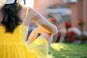 Young woman relaxing outdoors on sunny summer day. Happy lady sitting on green grass lawn daydreaming thinking. Calm girl enjoying