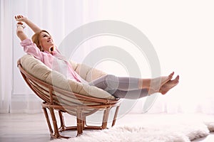 Young woman relaxing in papasan chair near window