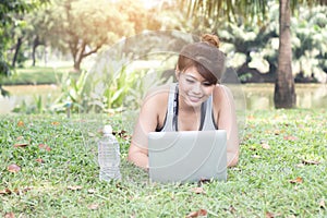 Young woman relaxing in the park, using a laptop on vacation day, Education and technology concept