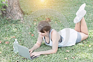 Young woman relaxing in the park, using a laptop on vacation day, Education and technology concept