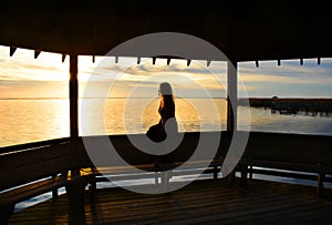 Young woman relaxing on pier on the lake at sunset.