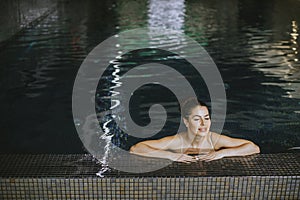 Young woman relaxing on the poolside of indoor swimming pool