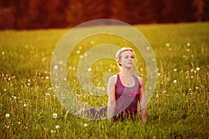 Young woman in a relaxing pose at the evening meadow