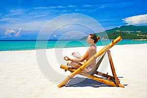 Young woman relaxing in pose yoga on a beautiful beach.