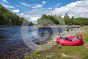 Young woman is relaxing in the red airlounger in the border of Fugga river in Hedmark county of Norway photo