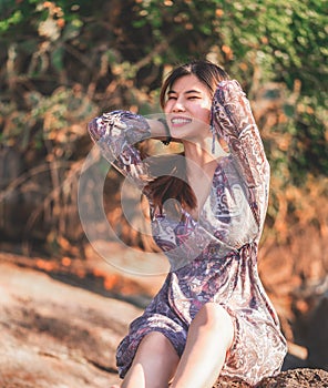 Young woman is relaxing on a rock on a Sunny Beach for Summer vacation relaxation and hapiness concept