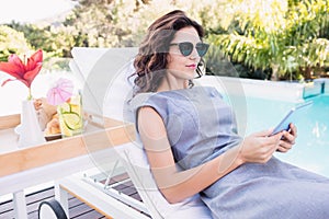 Young woman relaxing on a sun lounger near poolside