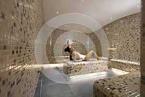 Young woman relaxing on the tepidarium bed in the spa