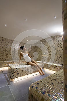 Young woman relaxing on the tepidarium bed in the spa
