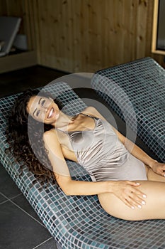 Young woman relaxing on the tepidarium bed in the spa