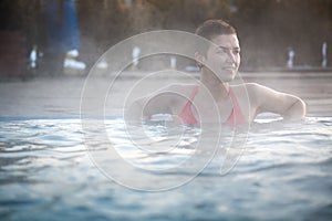 Young woman relaxing in thermal pool.