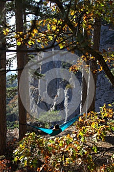 Young woman relaxing in the turquoise hammock in a mountains. Concept of relaxation and meditation