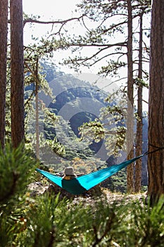 Young woman relaxing in the turquoise hammock in a wood. Concept of relaxation and meditation