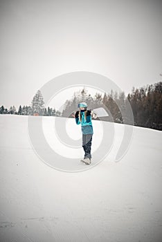 Young woman relaxing while walking up the hill to learn snowboarding