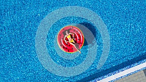 Young woman relaxing on watermelon in hotel resort pool. Top view of rich girl floating with fruit mattress drinking cocktail.