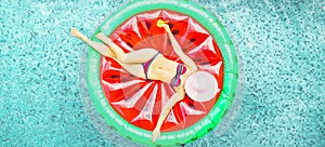 Young woman relaxing on watermelon lilo in hotel resort pool - Top view of rich girl floating with fruit mattress drinking