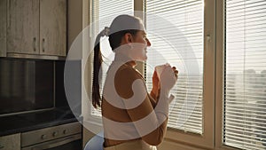 Young woman relaxing at window in morning with cup of tea or coffee. People in morning, beautiful cityscape