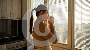 Young woman relaxing at window in morning with cup of tea or coffee. People in morning, beautiful cityscape, having break at