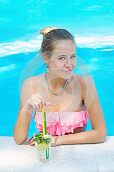 Young woman relaxiwith refreshing lemonade in the pool