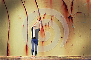 Young woman removes rust from wall